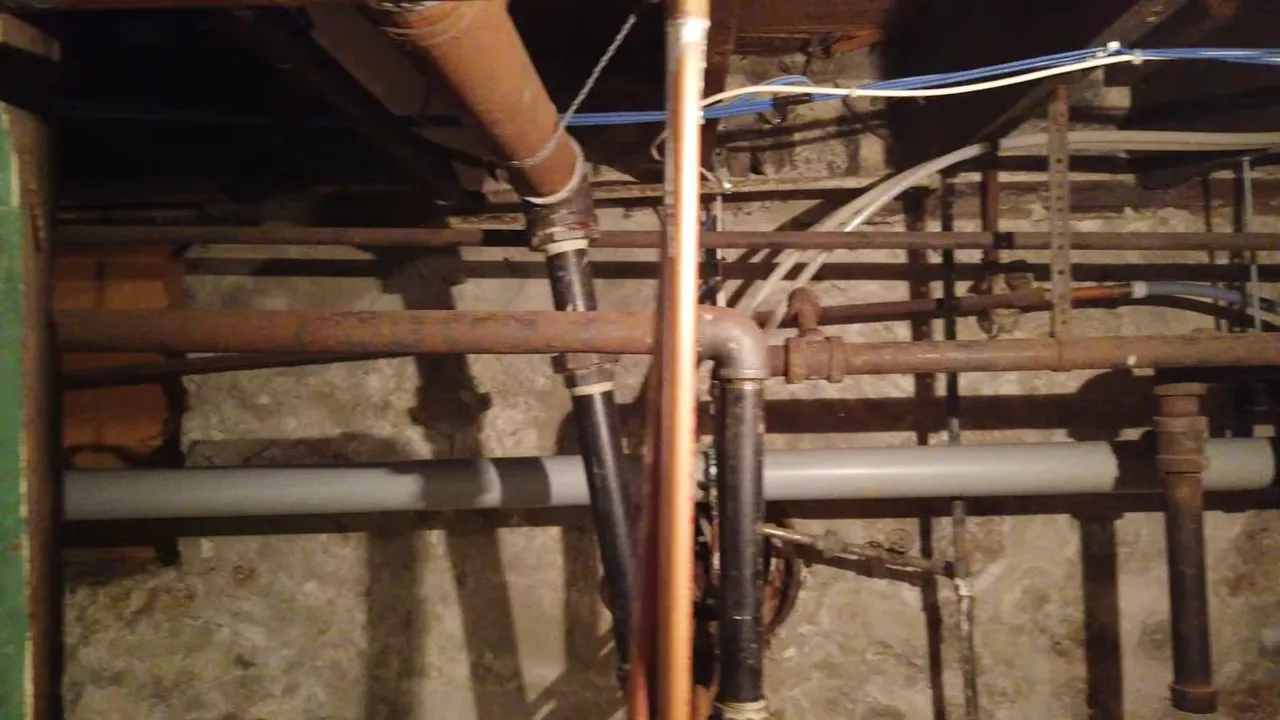 Exposed basement water pipes running between floor joists