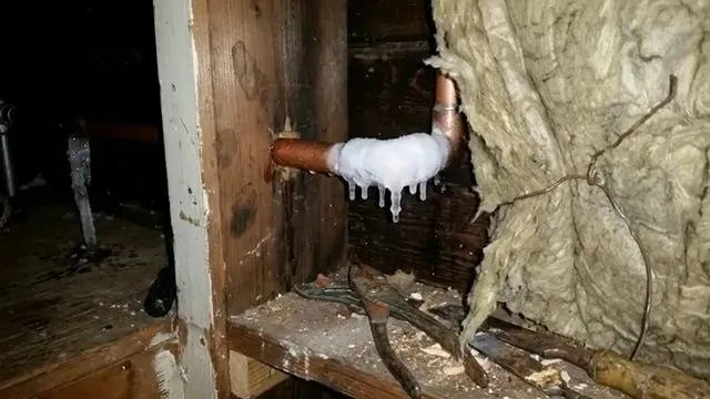Frozen copper elbow beside wall insulation