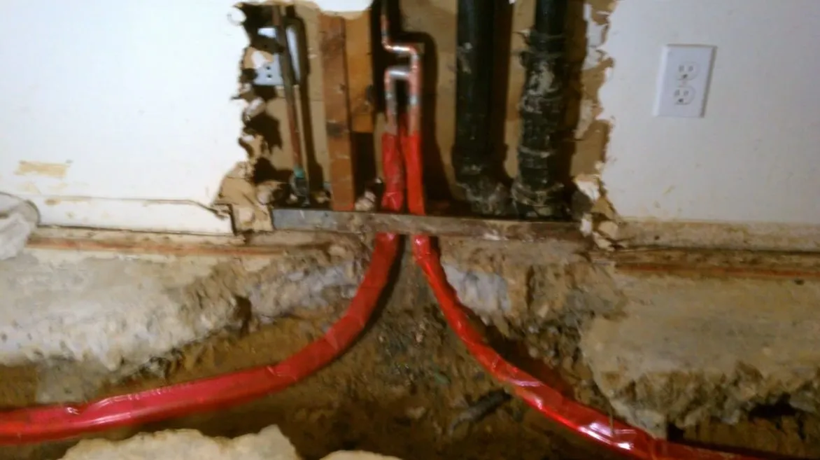 Water heater pipes beneath an open wall