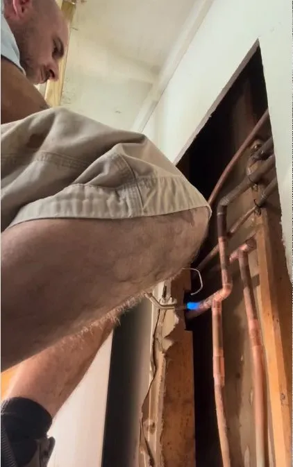 Worker looking for a leak in a wall opening